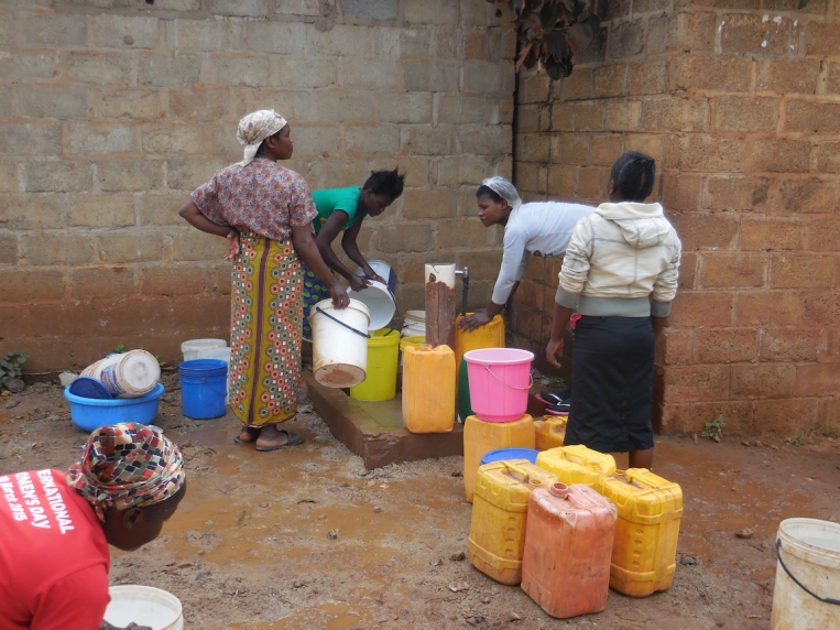 Neighbours filling their water containers to bring home. I saw women make multiple trips, just to get water, as they don't have any plumbing (or electricity) in their homes.